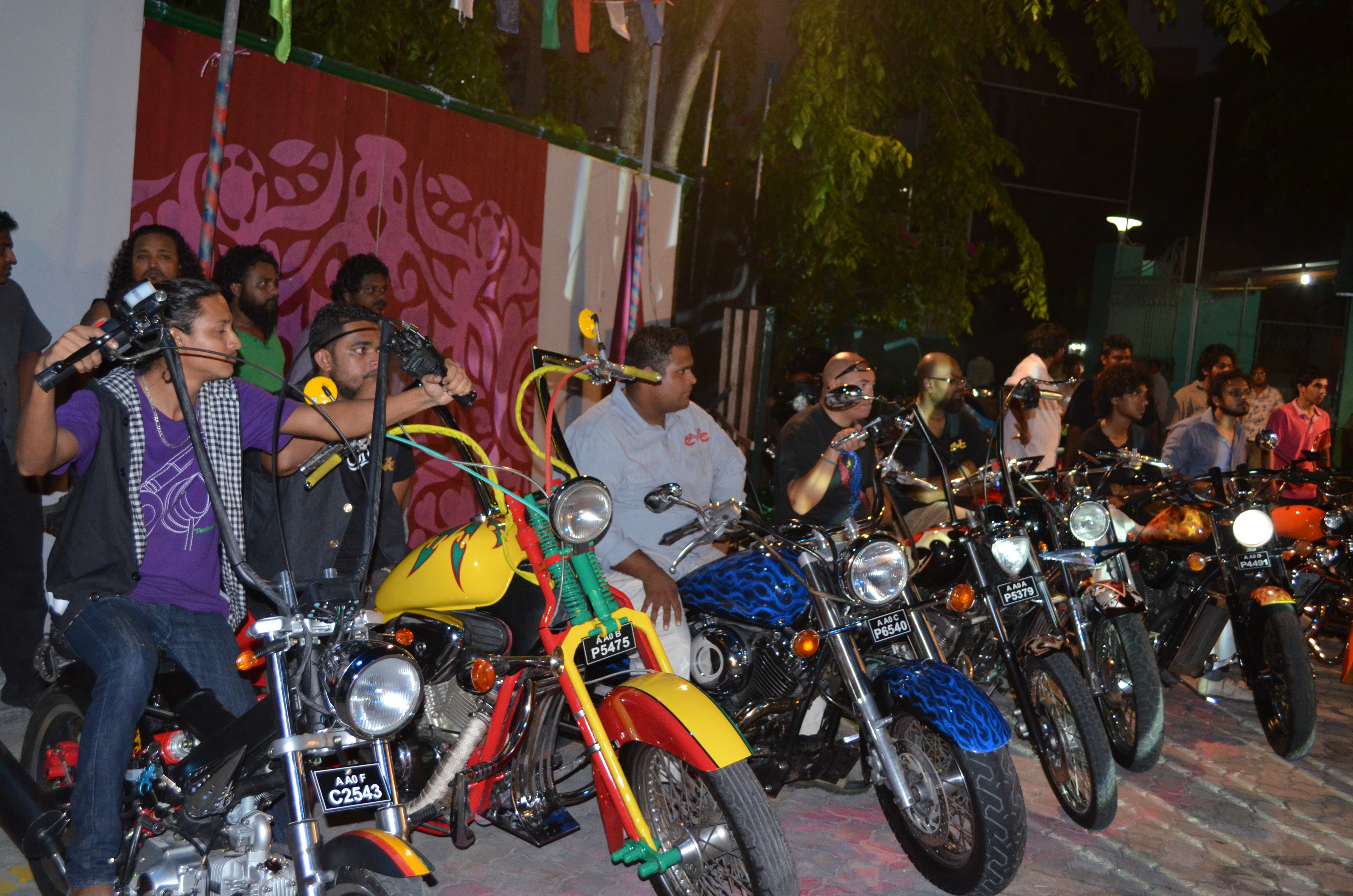 MCC custom motorcycles lined up at a night event
